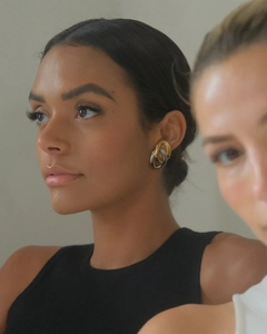Close-up of dual-tone 18K gold and silver intertwined oval earrings on a model