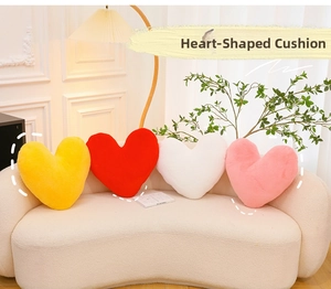Detail of soft heart-shaped plush pillows in yellow, red, white and pink on a sofa
