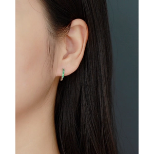 Close-up of S925 silver hoop earring with green stones worn by a female model