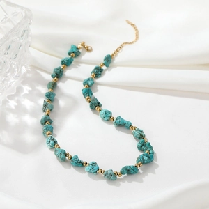 Detail of blue turquoise stone necklace with small gold beads on white silk backdrop