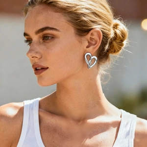 Close-up of heart-shaped silver earring with twisted texture worn by a model