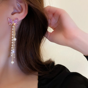 Detail of purple butterfly tassel earrings with faux pearls and crystals on a model