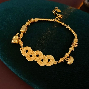 Macro detail of golden calabash bracelet with ancient coins on green velvet surface