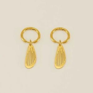 Detailed macro of gold hollow-out wing charms on stainless steel hoop earrings