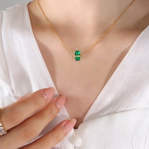 Elegant gold necklace with rectangular emerald green crystal pendant on female model
