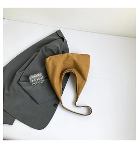 Detail of a mustard hobo bag with faux suede texture next to a dark grey blazer