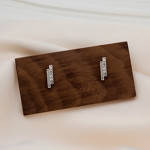 Macro shot of silver drop earrings with five sparkling cubic zirconia on a wooden display
