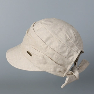 Detail of light beige cotton linen cap showing metal logo and elegant back bow knot