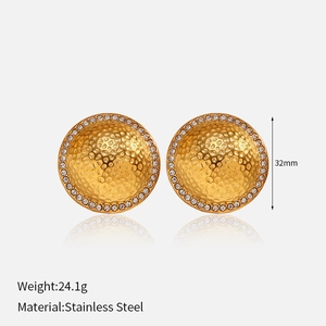 Macro detail of gold stainless steel earrings with hammer texture and white zircon stones