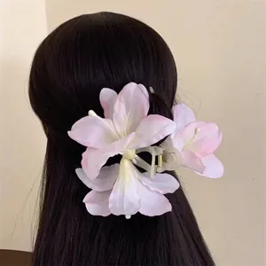 Close-up of a large lily flower hair claw clip with pink and white gradient petals