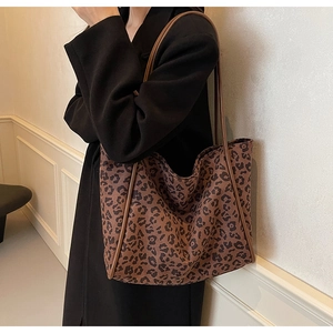 Close-up of leopard print canvas tote bag with leather trim worn by a model