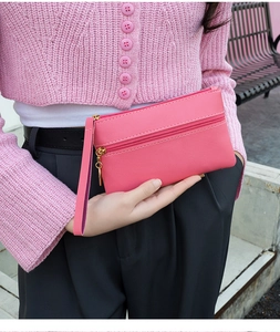 Close-up of rose red leather wristlet bag with double zippers and textured finish