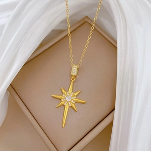 Elegant gold starburst necklace with zircons displayed in a beige jewelry gift box