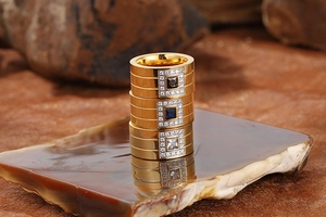 Close-up of three gold-plated stainless steel wide rings with black, blue, and white stones