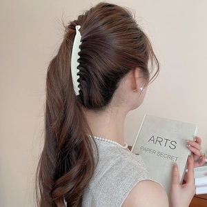 Détail d'une pince banane en acrylique blanc crème mat avec dents pour fixer les cheveux