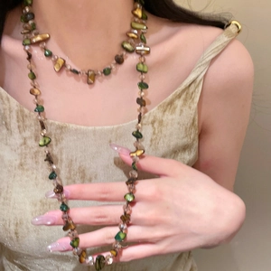 Close-up of vintage layered shell and bead necklace styled on a model's outfit