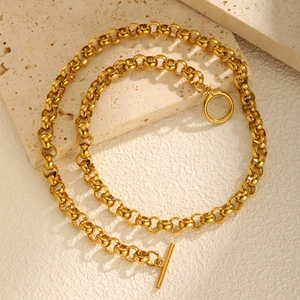 Detailed view of golden OT toggle clasp necklace on natural stone textured slabs