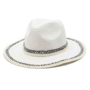 Detail of white straw sun hat with woven texture, pearl beads and silver stud accents