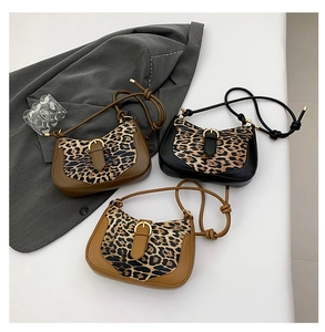 Three leopard print crossbody bags in black and khaki shown on a grey blazer
