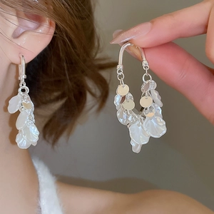 Détail de boucles d'oreilles pampilles à pétales de perles avec délicats charms floraux blancs