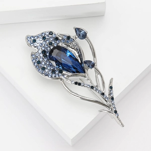 Exquisite silver feather brooch with blue crystal teardrop and rhinestones on white blocks