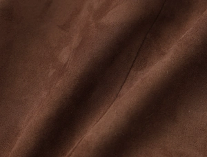 Gros plan de la texture du daim marron foncé avec des plis naturels sur le vêtement