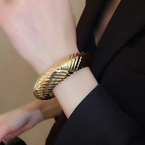 Vue macro du bracelet jonc croissant doré avec texture spirale polie sur tissu noir