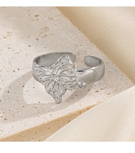 Detail shot of a polished silver butterfly ring with adjustable open band on silk fabric