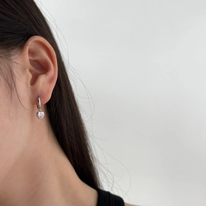 Detail of silver S925 heart earrings with zircon stones worn by a female model