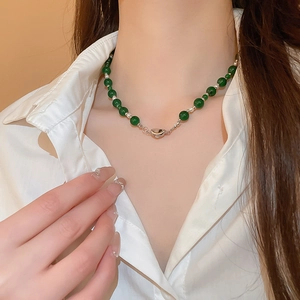 Détail d'un collier de perles vert émeraude avec des perles d'argent et fermoir