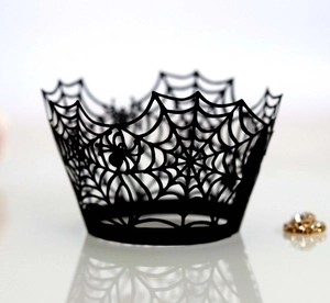 Close-up of laser-cut Halloween cupcake wrappers with intricate black spider web patterns