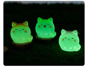 Luminous cartoon cat figurines glowing in the dark on rustic wood slices