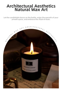 Close-up of scented candle in black glass jar burning on vintage desk with pine cones