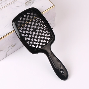 Black hollowed-out vent hairbrush for blow drying and styling on a white marble gift box