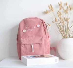 Detail of pink corduroy backpack featuring Sophia custom embroidery and floral accents
