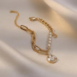 Detail of gold chain bracelet with freshwater pearls, smiley charm and number 5 pendant