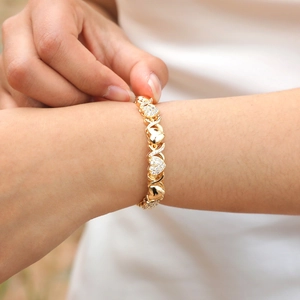 Close-up of golden heart and X link bracelet with zircon stones worn on wrist