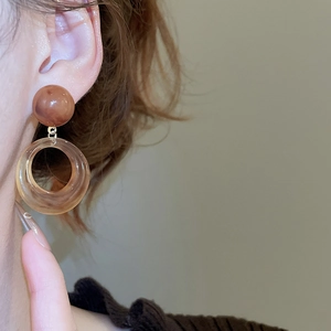 Close-up of resin wood drop earrings with marble beads and hollow ring design