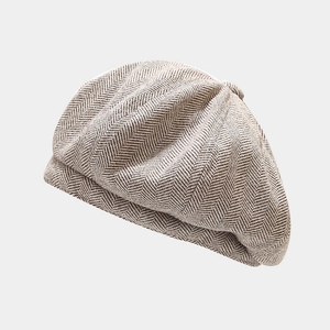 Close-up of herringbone pattern fabric on a vintage brown tweed newsboy cap with top button