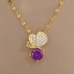 Close-up of golden butterfly pendant with purple crystal and small clear stones
