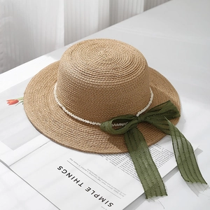 Detail of boater hat texture with elegant pearl trim and a green organza bow accent