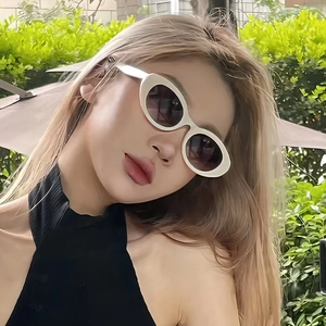 Chic white oval sunglasses with gradient lenses worn by a model in outdoor setting