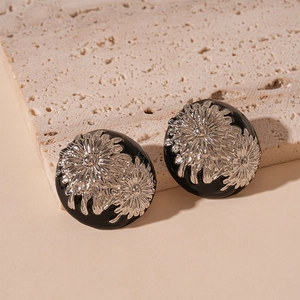 Close-up of vintage black round earrings featuring silver daisy flower relief details