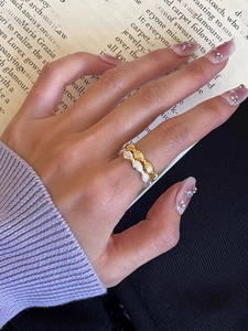 Detailaufnahme gewellter Muschel-Silberringe in Gold und Silber am Finger eines Models