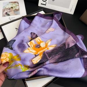 Close-up of purple silk scarf with yellow lotus and butterfly patterns on a tray