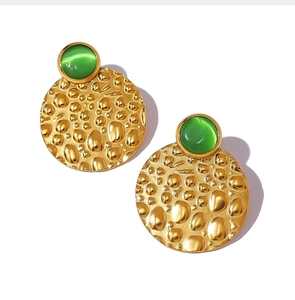 Detail of vintage hammered gold stud earrings with a smooth green cat-eye stone inlay