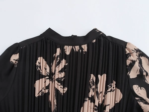 Close-up of pleated neckline and beige floral print on black women's dress fabric