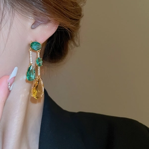 Détail de boucles d'oreilles pendantes jaunes et vertes portées par un mannequin