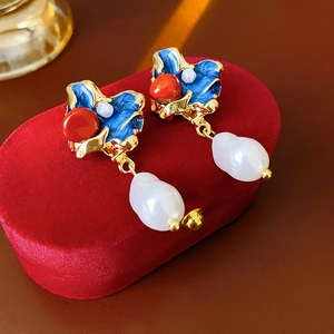Dettaglio degli orecchini vintage con smalto blu e perle barocche su velluto rosso