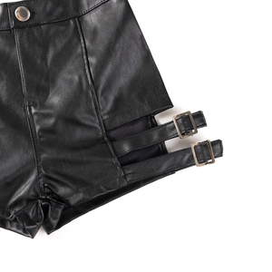Dettaglio di pantaloncini neri in ecopelle con fibbie metalliche e aperture laterali